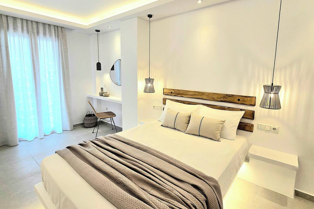 Un dormitorio moderno con una cama grande, mesitas de noche, un escritorio y una silla.