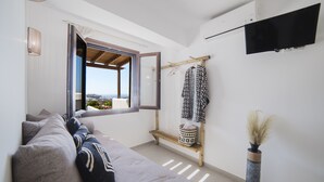 Una sala de estar moderna con un sofá, una ventana, un televisor y un perchero.