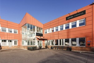 A modern hotel building with a clear sign reading "HOTEL VINDEUS."