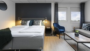 A modern hotel room with a bed, a sofa, a coffee table, and a chair. - Hotel Vindeus (Sodertalje)