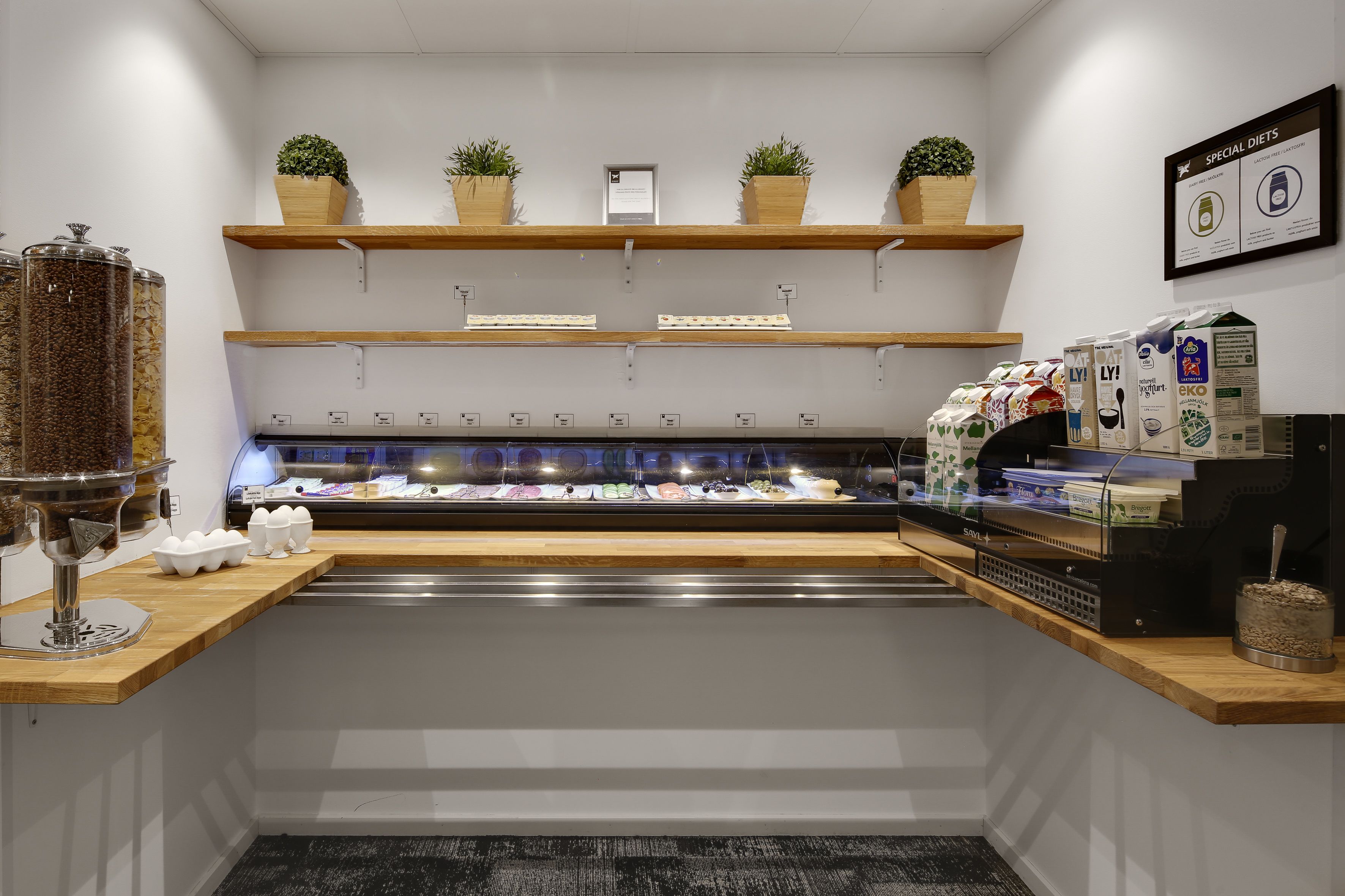 Una barra de desayuno con diversos alimentos, como huevos y productos de pastelería, y una exhibición de productos lácteos.