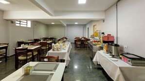 A spacious dining area with multiple tables and chairs, equipped with various food service appliances and supplies. - Hotel Cardim Plaza (São Paulo)