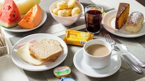 A table set with breakfast items including toast, ham, cheese, fruit, and a beverage. - Hotel Cardim Plaza (São Paulo)