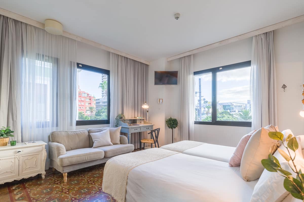 Una habitación de hotel con cama, sofá, escritorio y televisor.
