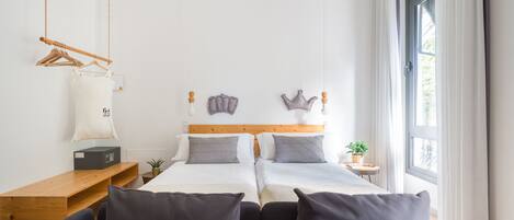 Een moderne hotelkamer met een groot bed, een houten bureau, een hanglamp en een groot raam met gordijnen.