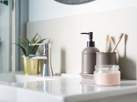 Un lavabo de salle de bain avec un robinet moderne, un flacon-pompe et un pot de savon.