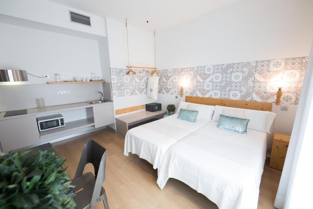 Ein modernes Schlafzimmer mit einem Bett, Nachttischen, einem kleinen Schreibtisch und einer Mikrowelle.