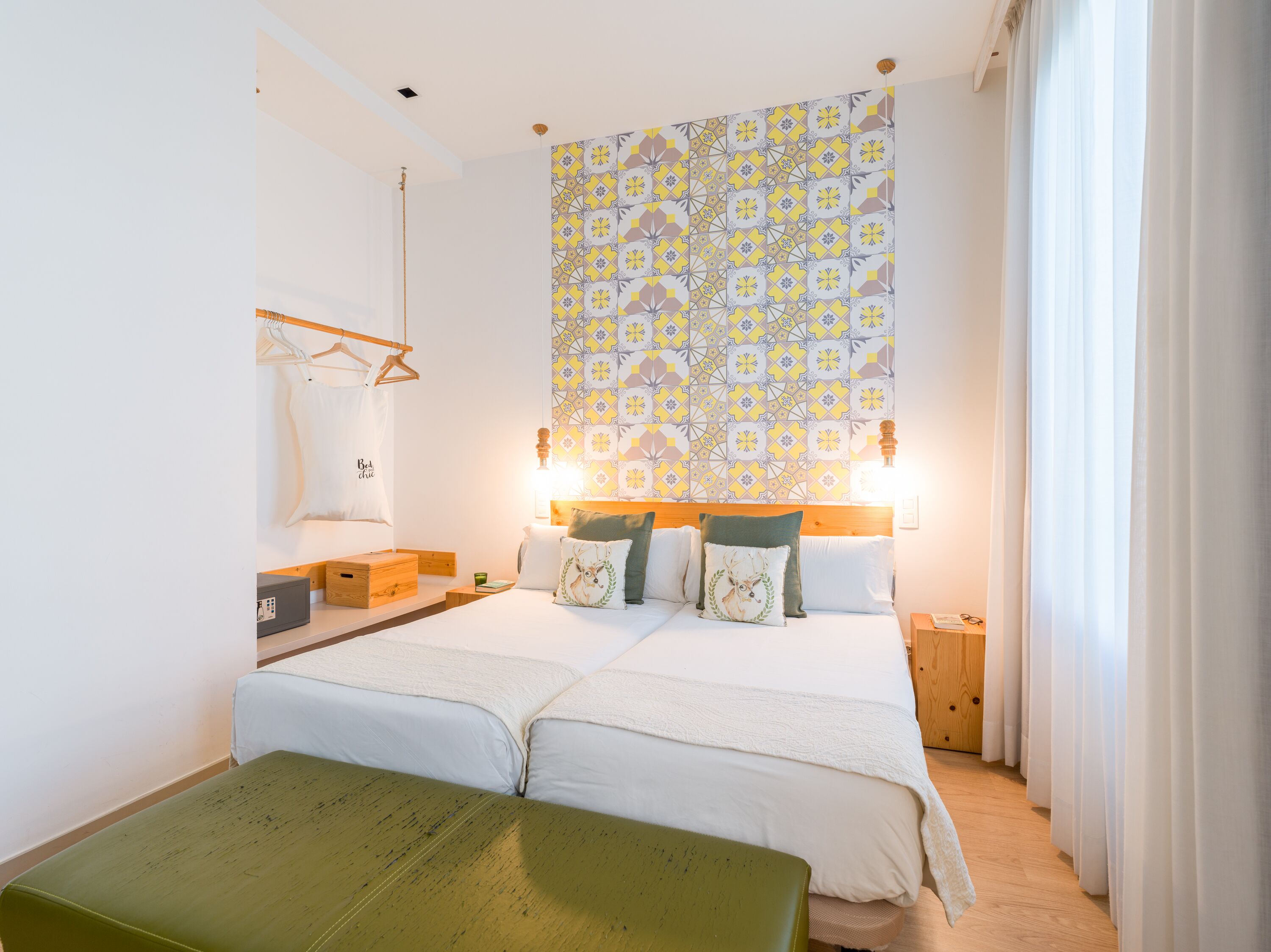 Un lit double avec une tête de lit en bois, une table de chevet avec une lampe et une tapisserie à motifs accrochée au mur.