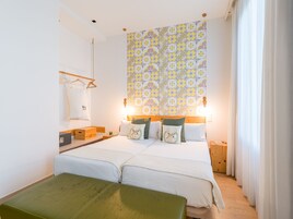 Un lit double avec une tête de lit en bois, une table de chevet avec une lampe et une tapisserie à motifs accrochée au mur.