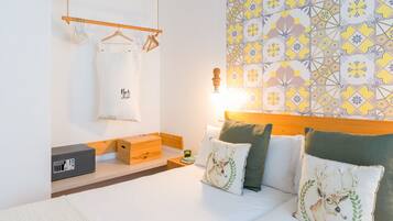 Een verzorgde hotelkamer met een bed, nachtkastje en een wand met behangpapier met een geometrisch patroon.