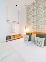 A neatly arranged hotel room with a bed, bedside table, and a wall with a geometric patterned wallpaper.