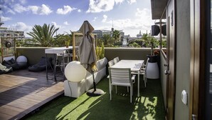 Una terraza en la azotea con piso de madera, mobiliario exterior y vistas al horizonte de la ciudad.