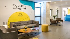 Una hall moderna con una poltrona, sedie, un tavolino da caffè e una parete con la scritta 'COLLECT MOMENTS'.
