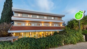 Un hotel su due piani con tetto in tegole rosse, un ingresso accogliente e un cartello che indica che si tratta di un hotel per viaggiatori.