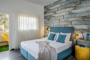 Une chambre à coucher moderne avec un grand lit, un mur en briques apparentes et une chaise jaune près de la fenêtre.