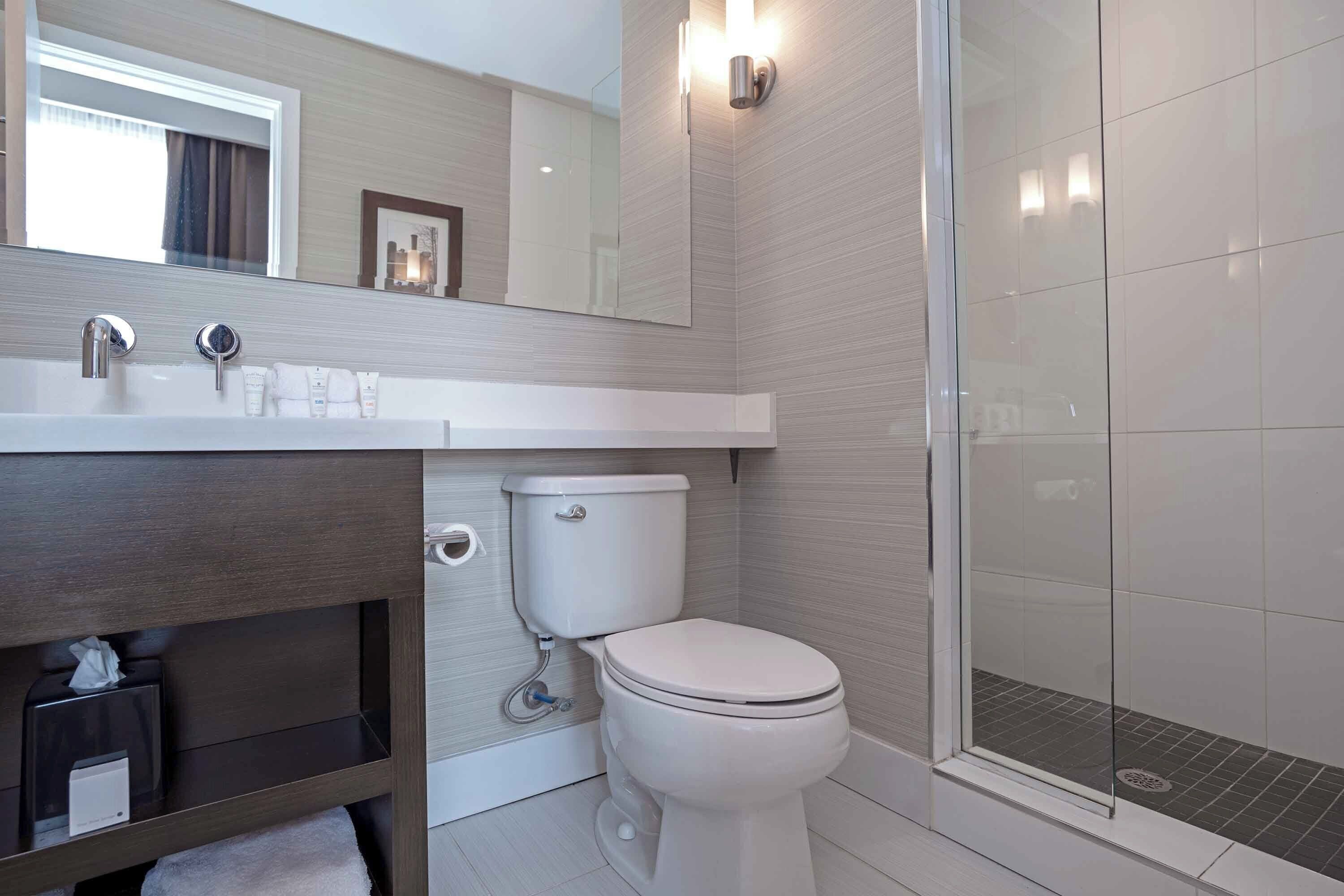 A modern bathroom with a toilet, sink, and shower.