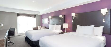 A hotel room with two beds, a desk, and a chair.