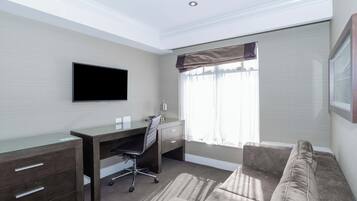 A hotel room with a desk, chair, and a large window with curtains.