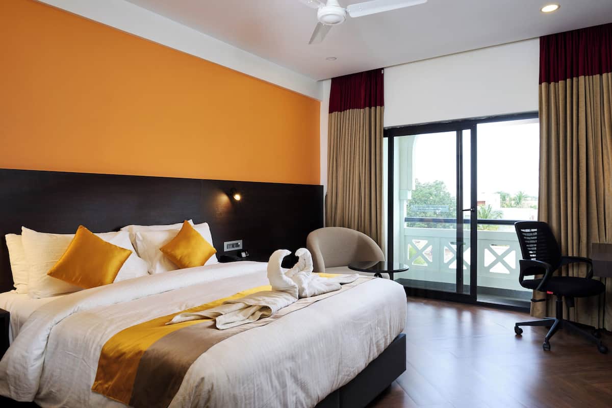 Une chambre d’hôtel avec un grand lit, un bureau avec une chaise et une vue sur l’extérieur grâce à une porte coulissante.