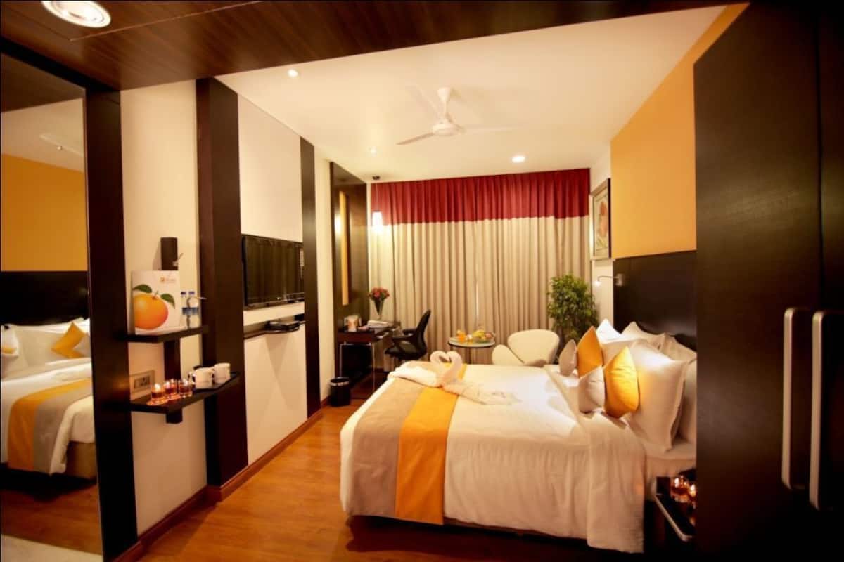 Une chambre d’hôtel avec un lit, un bureau, une chaise, une télévision et un miroir.