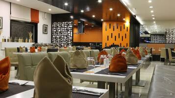 A modern restaurant with neatly arranged tables and chairs, a decorative wall with geometric patterns, and a clean, contemporary design.