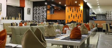 Un ristorante moderno con tavoli e sedie ben disposti, una parete decorativa con motivi geometrici e un design pulito e contemporaneo.