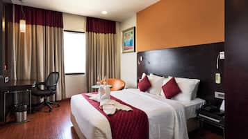 Una habitación de hotel con cama, escritorio, silla y una mesita con botellas.