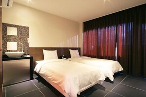 Ein Hotelzimmer mit zwei Betten, einem Nachttisch mit Lampe, einem wandmontierten Spiegel und einem großen Fenster mit Vorhängen.