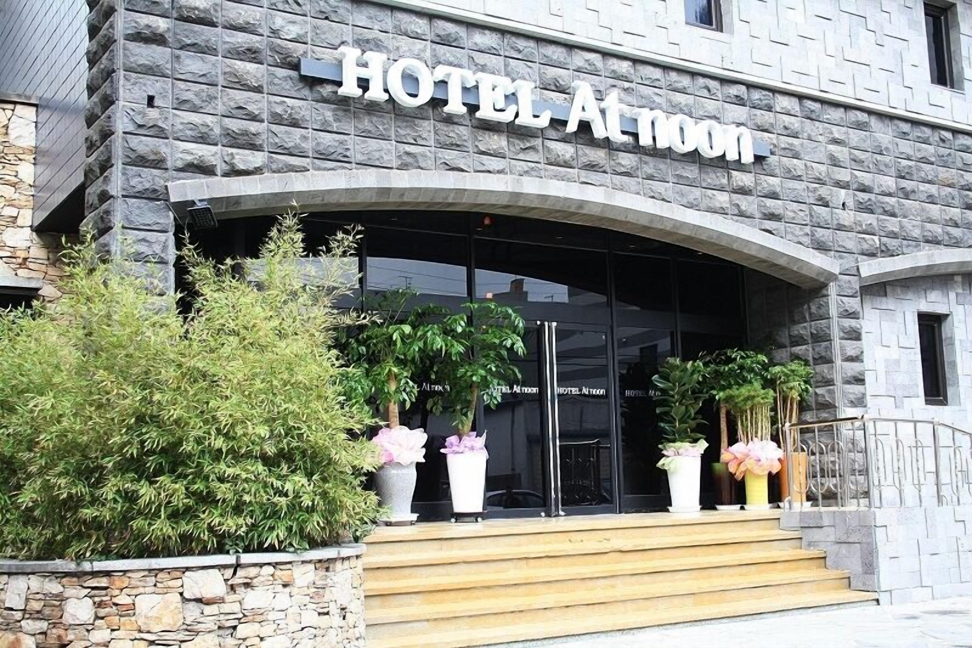 A hotel entrance with a stone facade and a sign reading "HOTEL ALMOON."