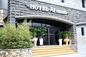 A hotel entrance with a stone facade and a sign reading "HOTEL ALMOON." - Hotel At noon (Jeju City)