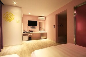 A hotel room with a bed, a desk with a flat-screen TV, a sink, and a mirror. - Hotel At noon (Jeju City)