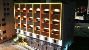 A multi-story hotel with a modern design, featuring a series of balconies and illuminated windows. - Hotel At noon (Jeju City)