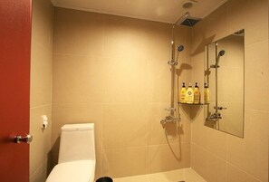 Ein Badezimmer mit Toilette, Dusche und Ablage für Toilettenartikel.