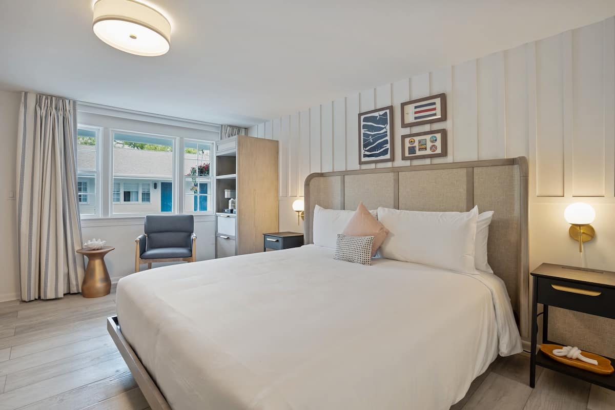 A hotel room with a large bed, bedside tables, a desk, and a chair.