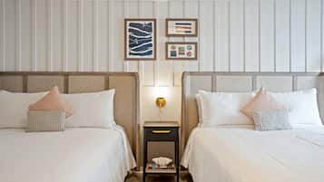A hotel room with two beds, a nightstand, and wall-mounted artwork.
