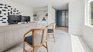 A modern kitchen with white cabinetry, a wooden island with two barstools, and a decorative wall art piece. - Greyfinch Chatham Inn (Chatham)