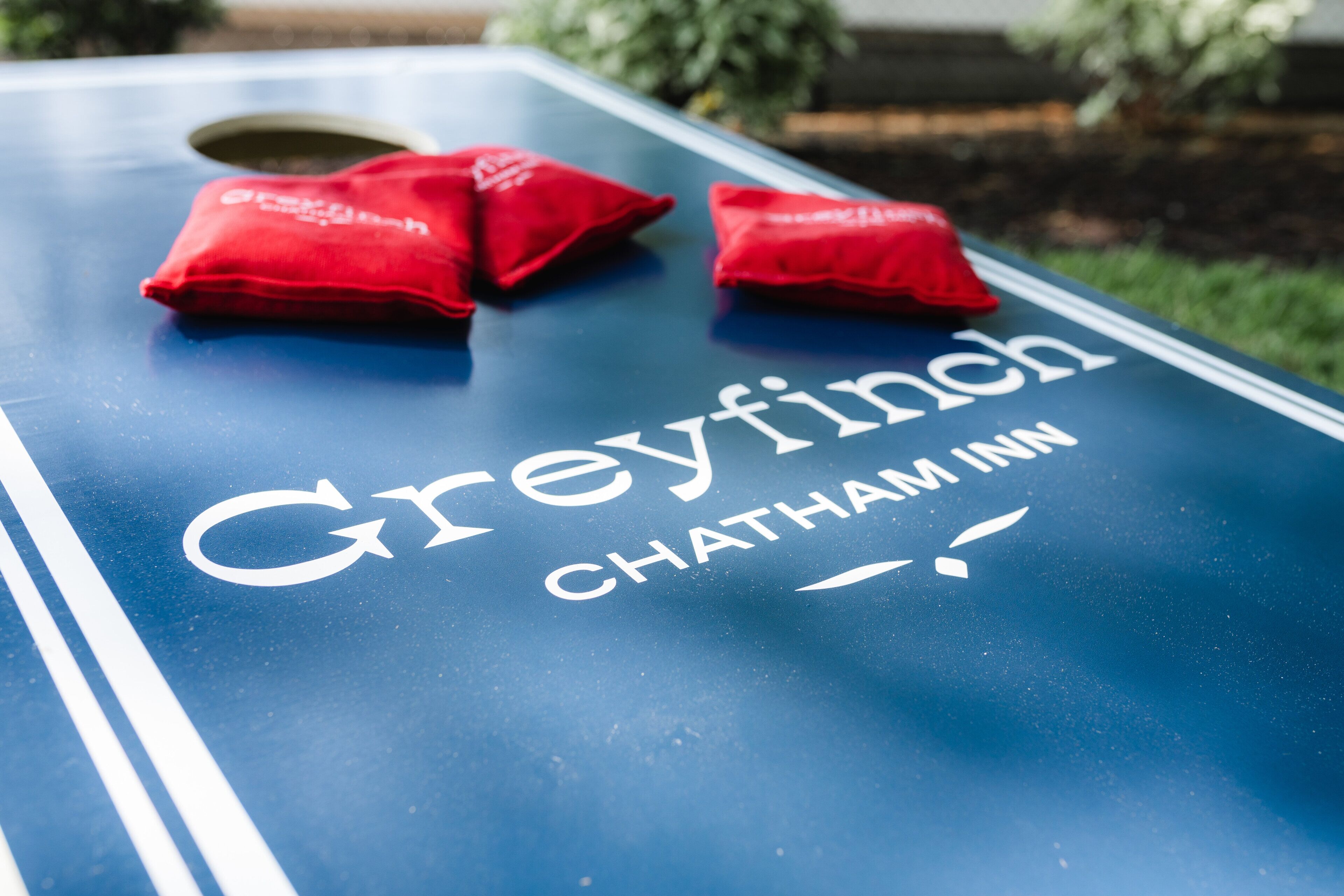 Et bord med teksten "Greyfinch Chatham Inn" og to røde puder.