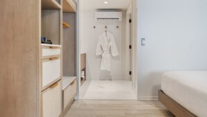 A modern bedroom with a wooden wardrobe, a white robe hanging on the door, and a bed with a wooden frame. - Greyfinch Chatham Inn (Chatham)