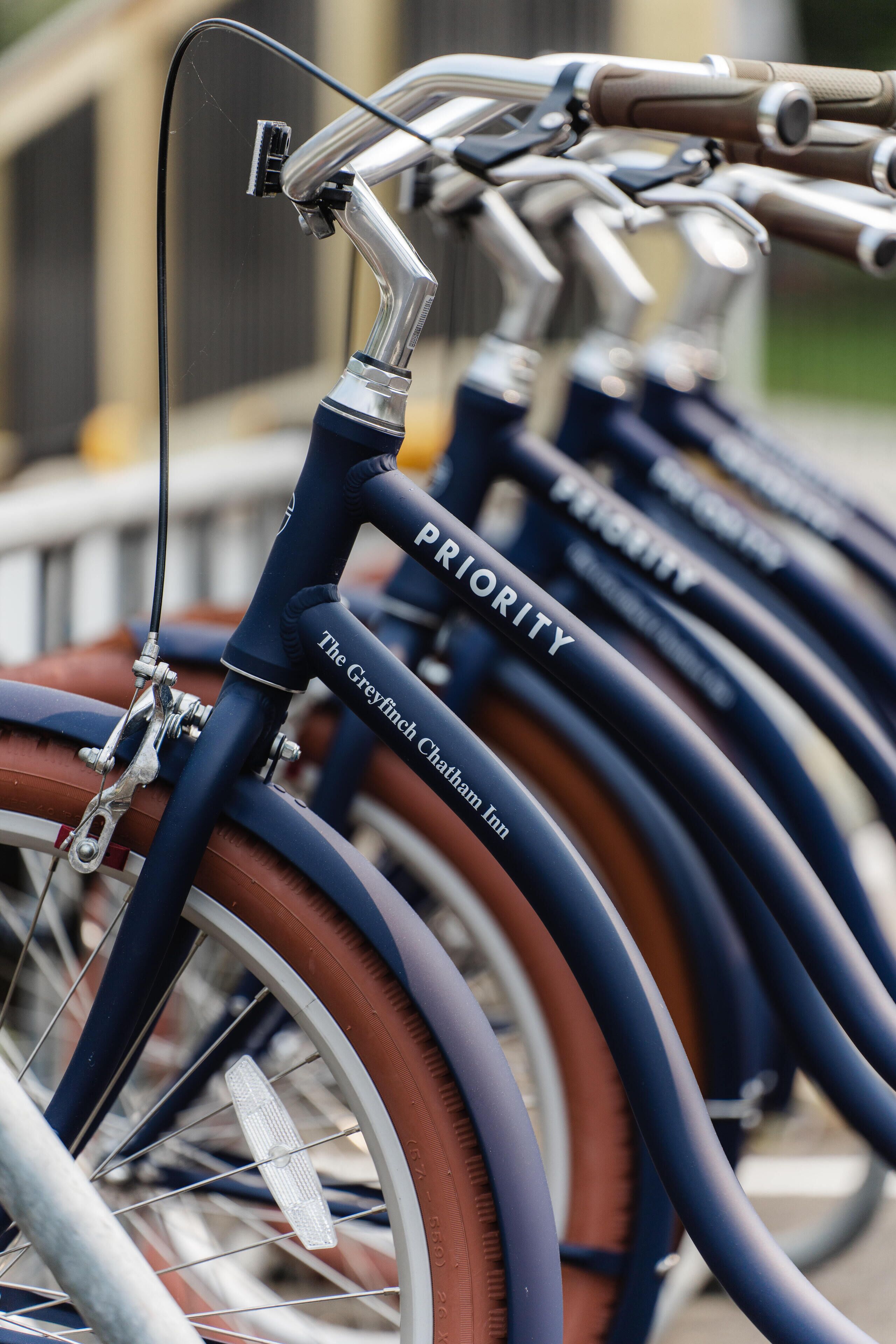 A row of bicycles with "PRIORITY" and "The Grey Finch Charter Inn" labels, indicating a bike-sharing program.