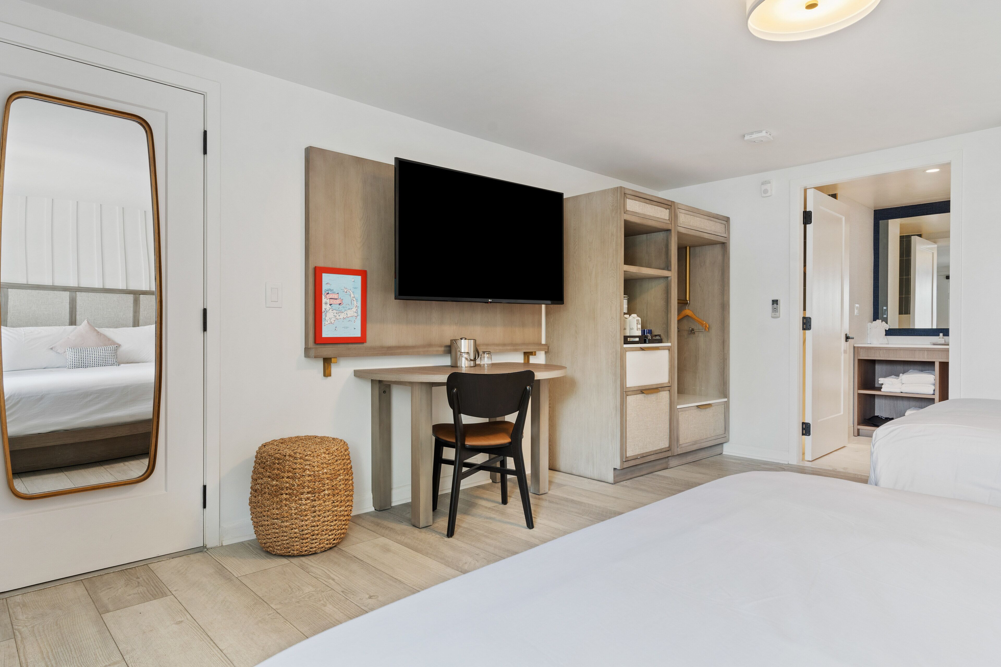 A hotel room with a bed, a desk with a chair, a television, and a wardrobe.