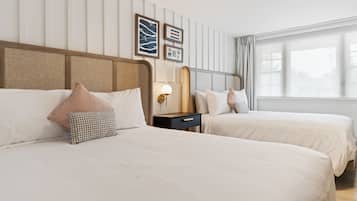 Habitación de hotel con dos camas, una mesita de noche, una lámpara de pared y cuadros enmarcados.