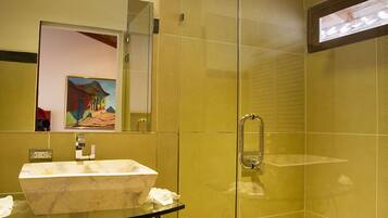 A bathroom with a marble sink, a glass shower enclosure, and a mirror reflecting a painting.