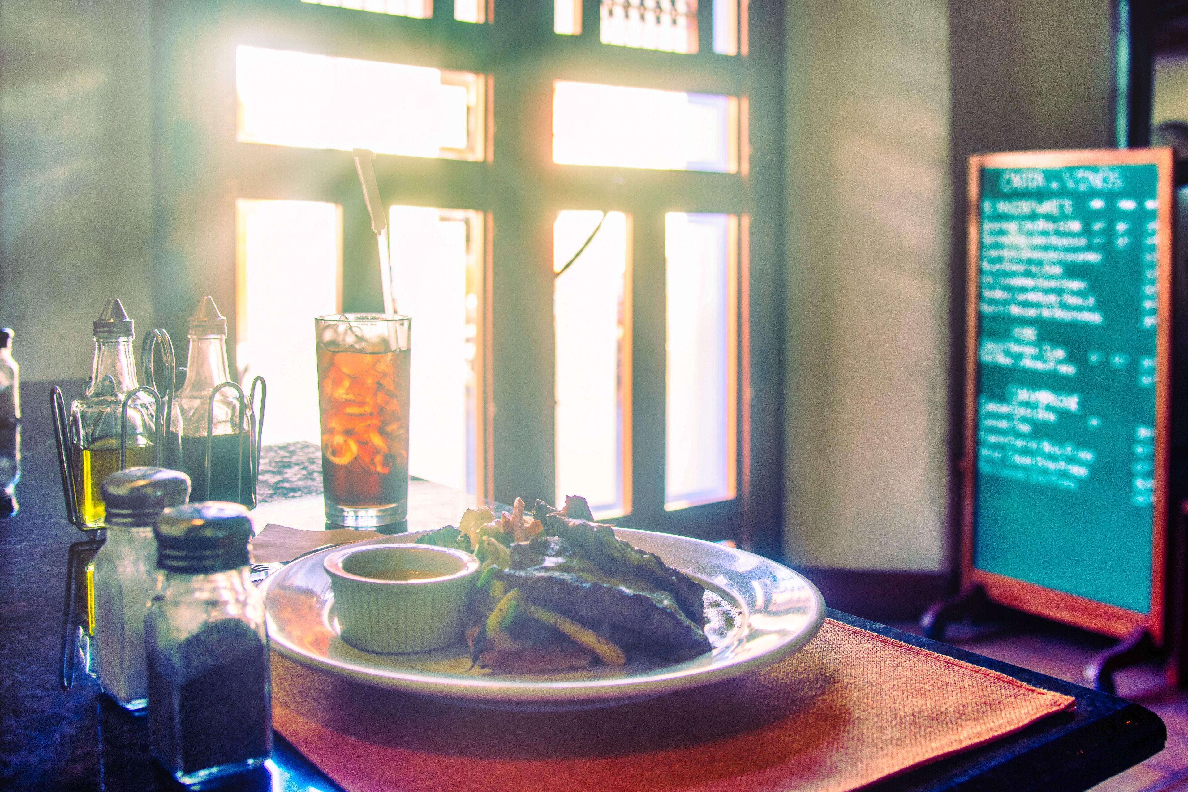 A dining table with a plate of food, a drink, and condiments.