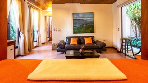 A hotel room with a large bed, a sofa, a painting on the wall, and a view of greenery through the window. - Estrada Hotel & Bistro (Granada)