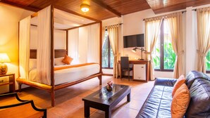 A four-poster bed with a desk and a sofa in a well-lit room with large windows. - Estrada Hotel & Bistro (Granada)