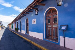 Una calle con un edificio azul que tiene ventanas arqueadas y un letrero.