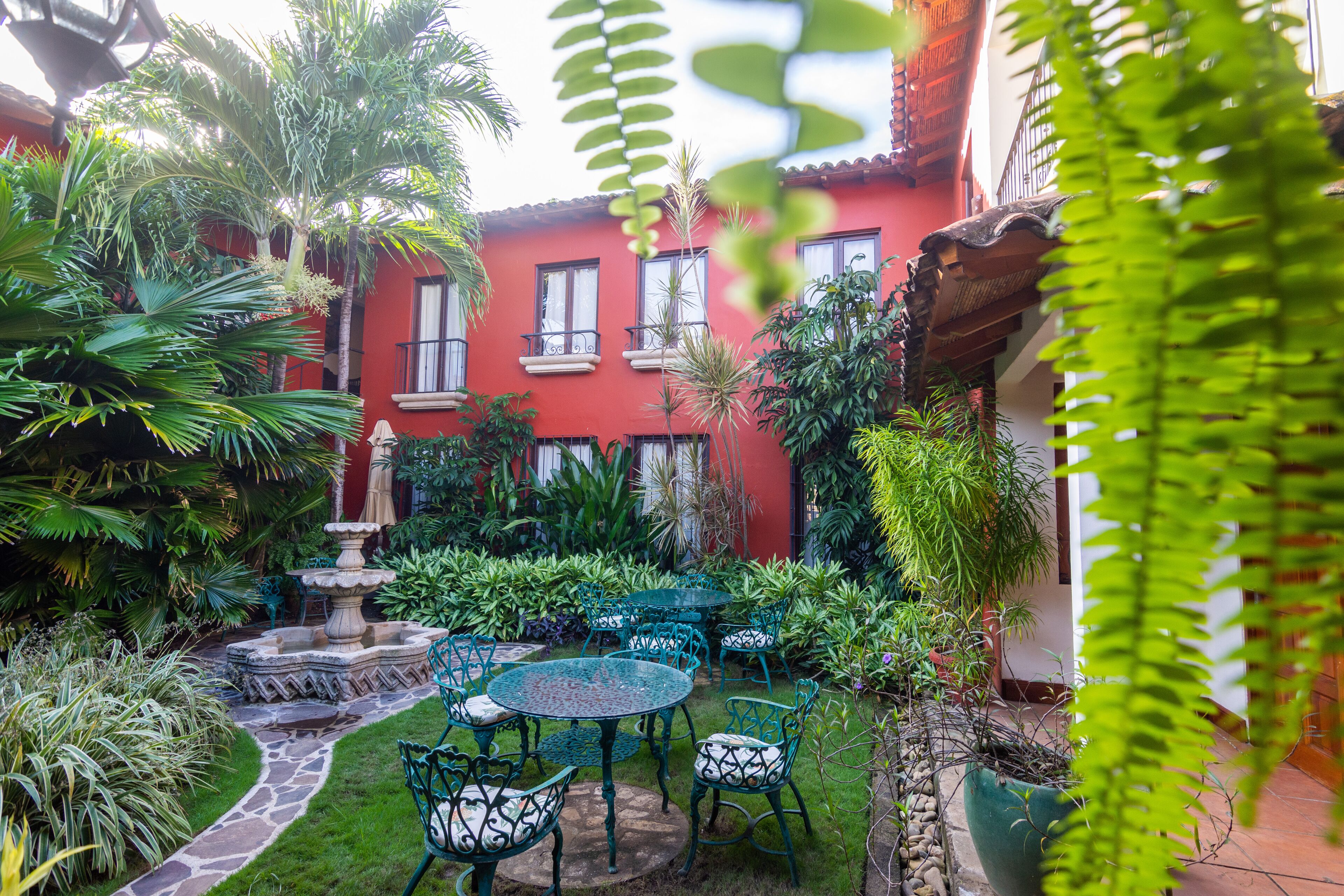 A courtyard with a red building, green plants, and outdoor seating.