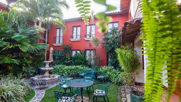 A courtyard with a red building, green plants, and outdoor seating.