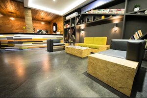 En moderne lobby med en træreception, en gul sofa og en bogreol.