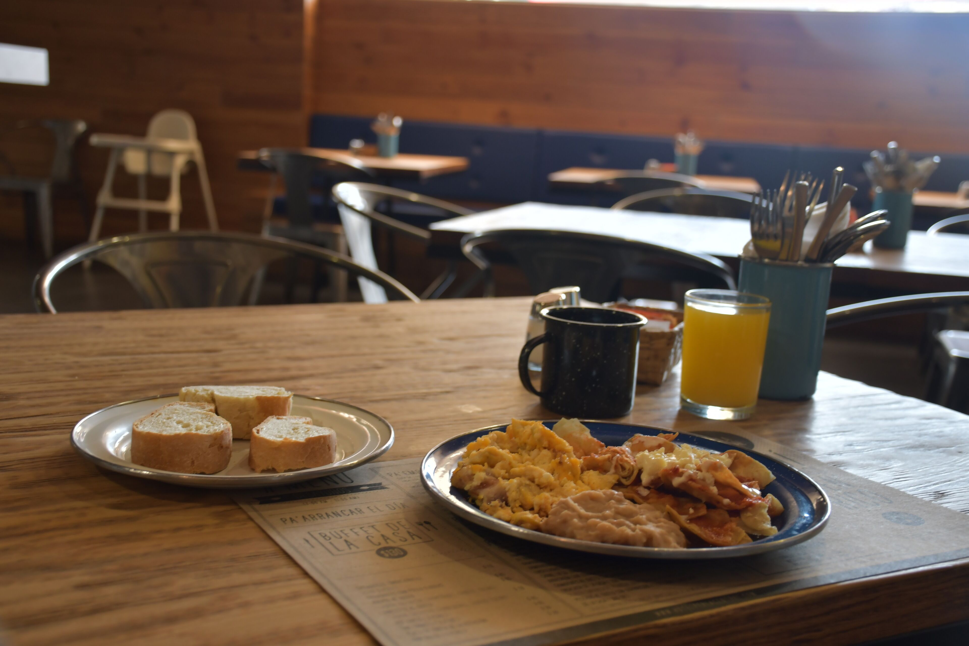 Una mesa de desayuno con pan, huevos revueltos y una bebida.